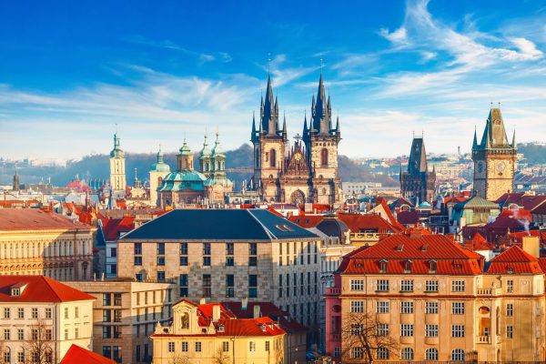 High spires towers of Tyn church in Prague city (Church of Our Lady before tyn cathedral) urban landscape panorama with red roofs of houses in old town and blue sky with clouds